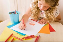 young girl drawing with crayons